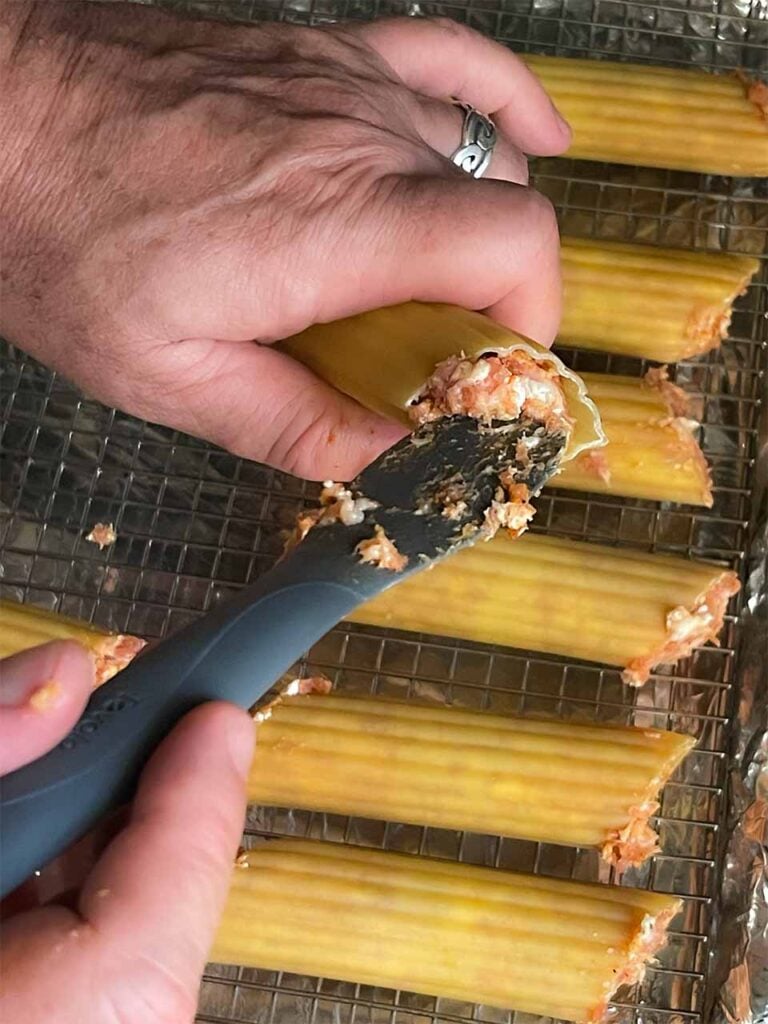 Stuffing the manicotti shells with the sausage mixture for smoked shotgun shells.