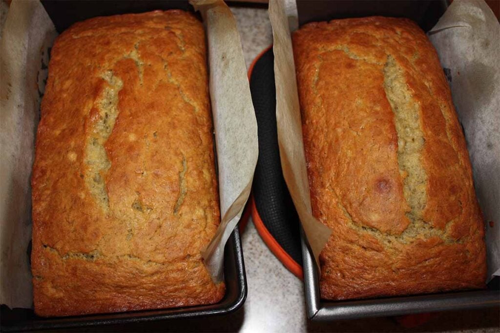Two loaves of banana bread in loaf pans.