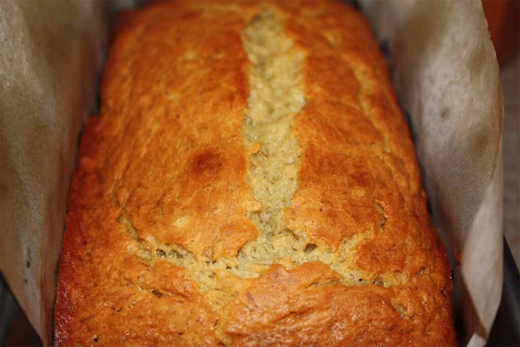 Banana bread in a parchment paper lined loaf pan.