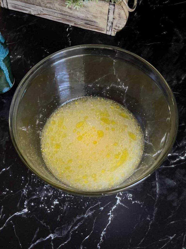 The wet ingredients for the focaccia mixed together in a glass bowl.