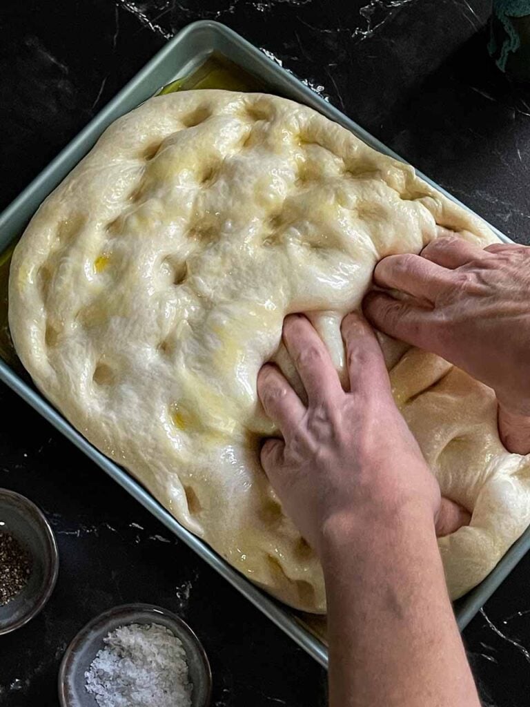 Adding dimples to the focaccia dough.