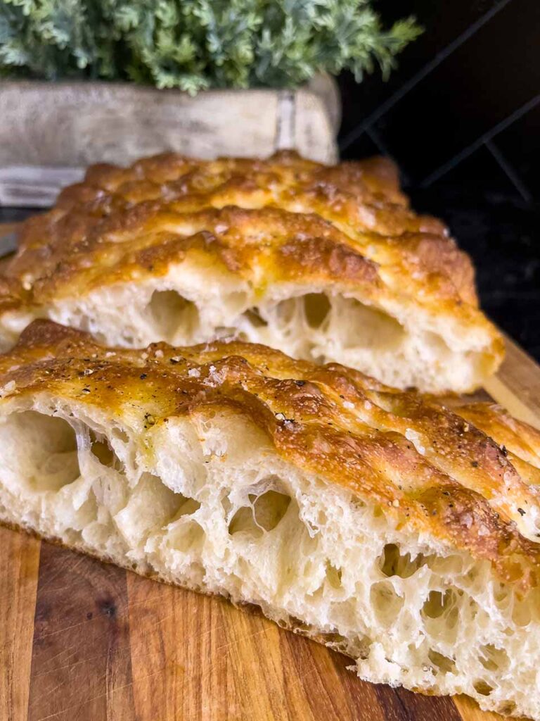 Cut focaccia bread on a wooden cutting board.