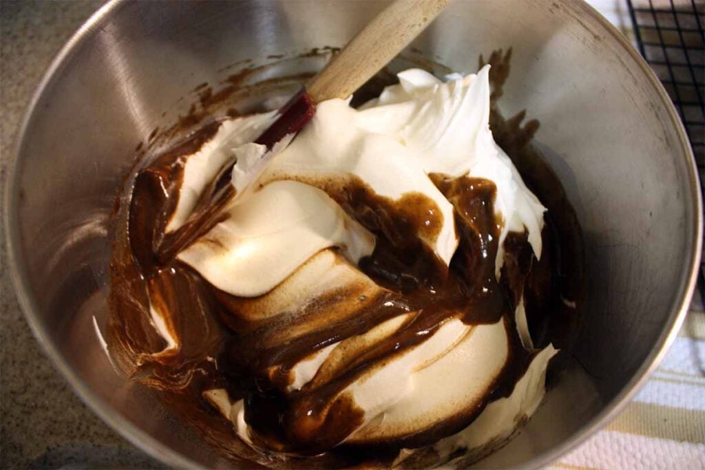 Whipped cream topping in a bowl folding with the pudding.