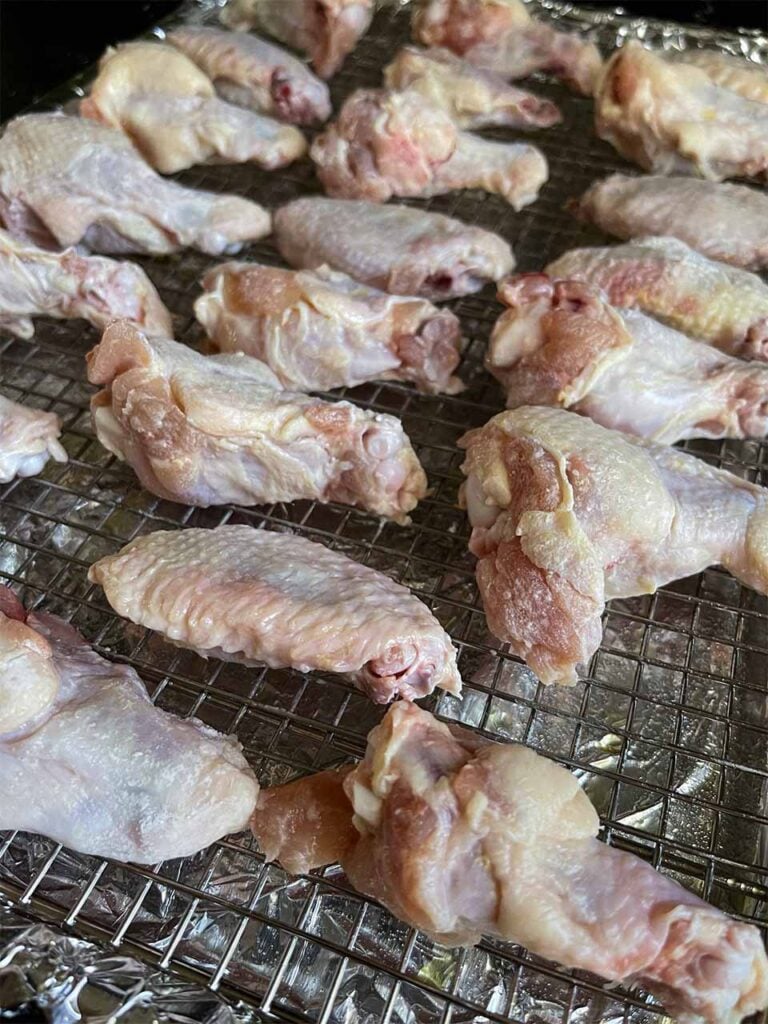 Raw chicken wings on a wire rack about to go into the oven.