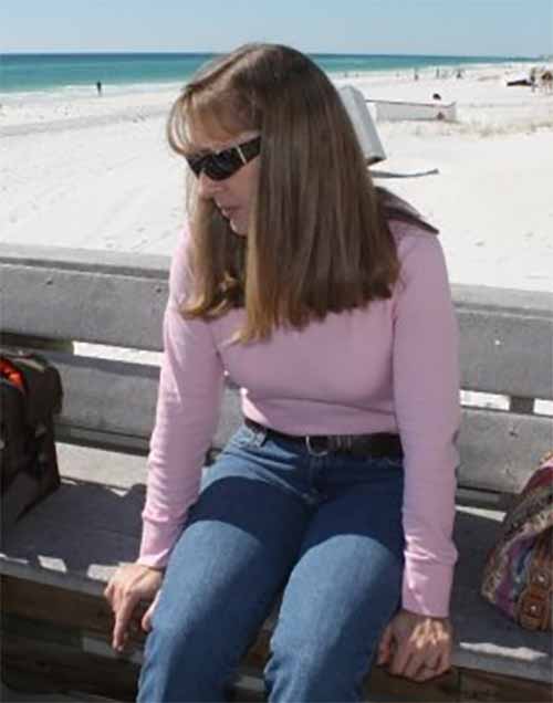 Leigh Harris sitting on a bench, beachside.