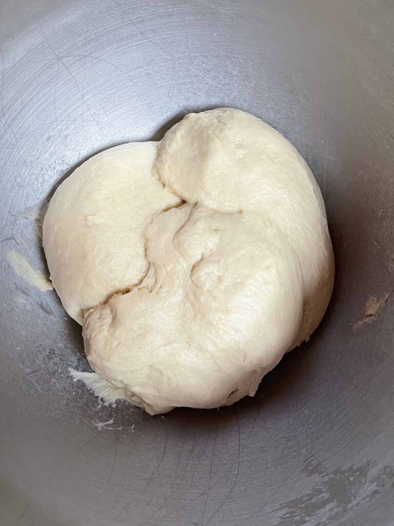Mixed crescent roll dough before rising in a metal bowl. 