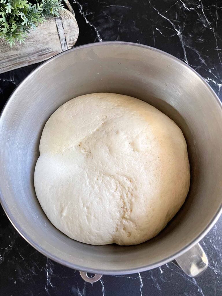 Risen crescent roll dough in a metal bowl.
