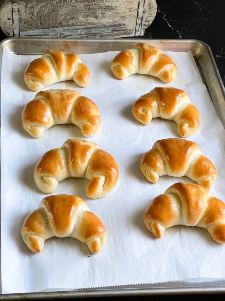 Baked crescent rolls on a parchment paper lined baking sheet.