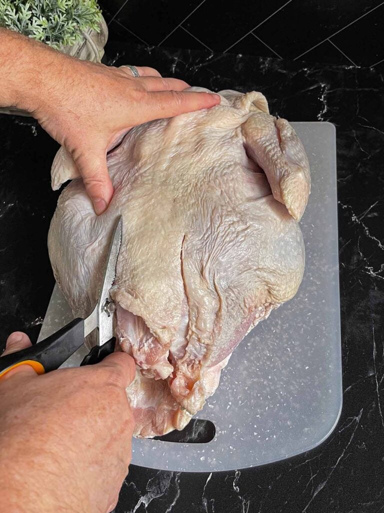 Removing the backbone of a turkey with kitchen shears.