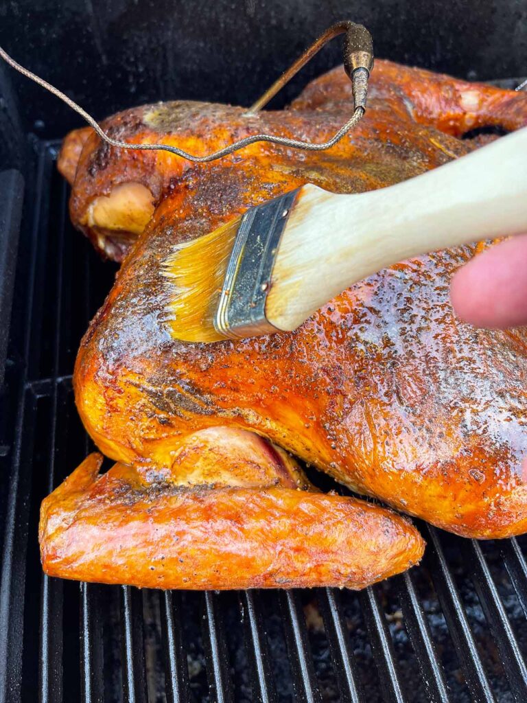 brushing butter over a roasting turkey on the Masterbuilt.