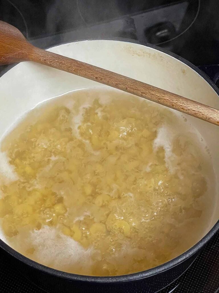 Elbow pasta boiling in a large stock pot.