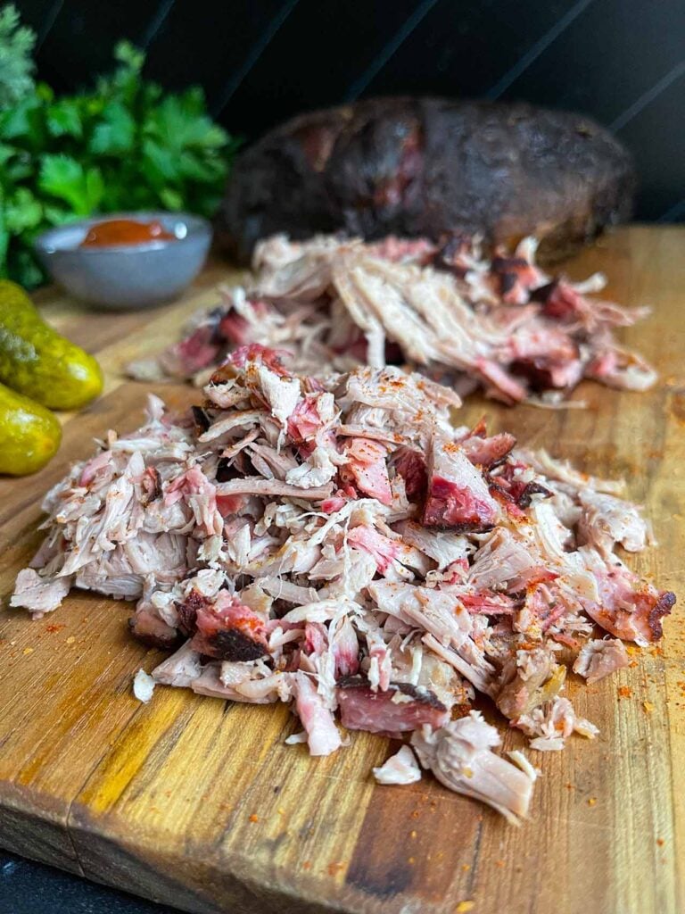 Chopped and shredded pork butt on a wooden cutting board.