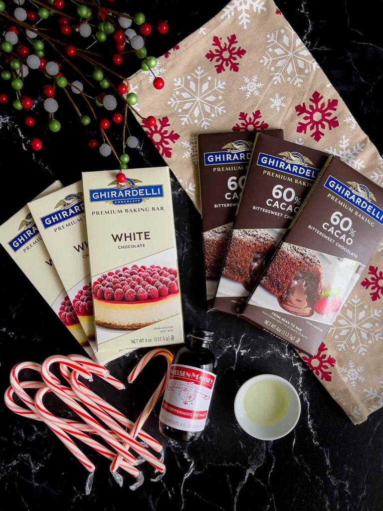 Ingredients needed to make dark chocolate peppermint bark on a dark surface with a Christmas napkin.