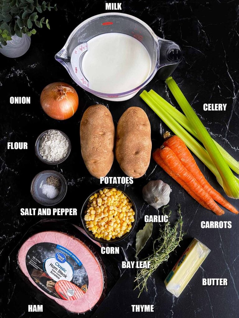 Ingredients for ham and potato soup on a dark surface.