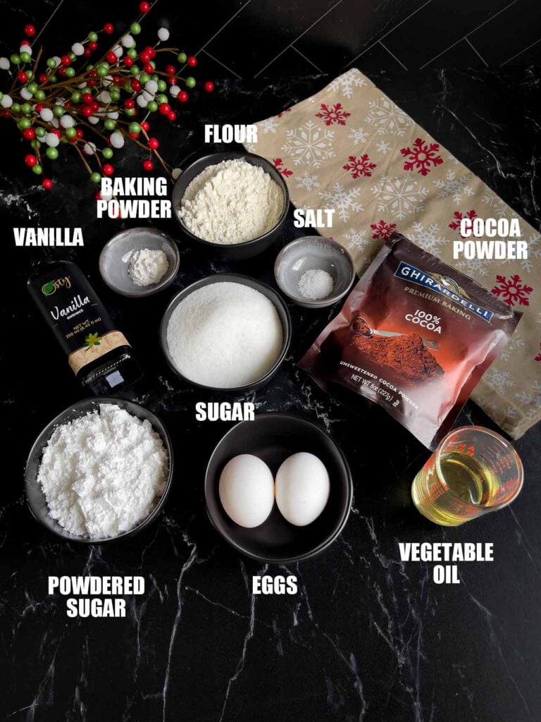 Ingredients for chocolate crinkle cookies on a dark surface.