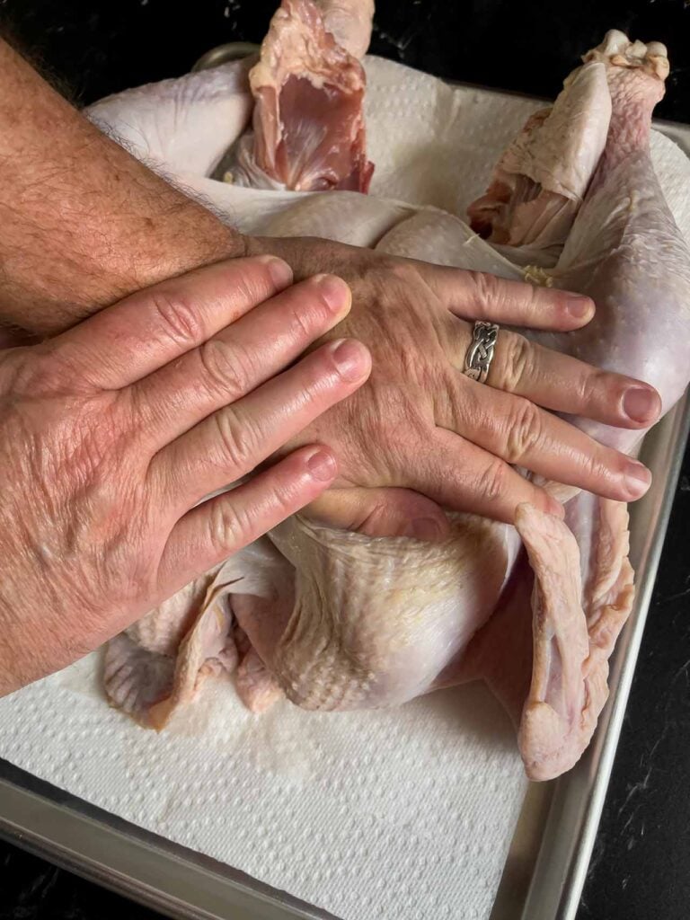 Breaking the breastbone of a turkey using the heels of the palm.