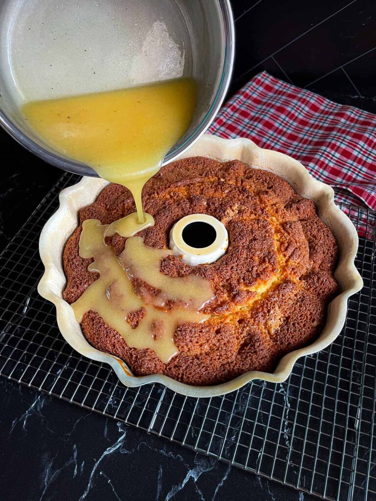 Eggnog glaze being poured over the eggnog bundt cake.