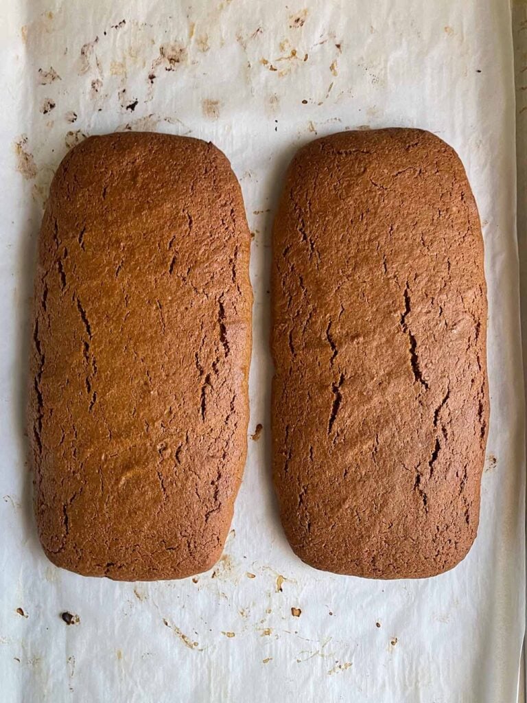 Baked gingerbread biscotti before slicing on a parchment paper lined baking sheet.