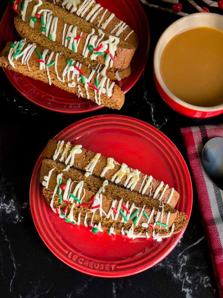 Gingerbread biscotti on a red plate with a cup of coffee.