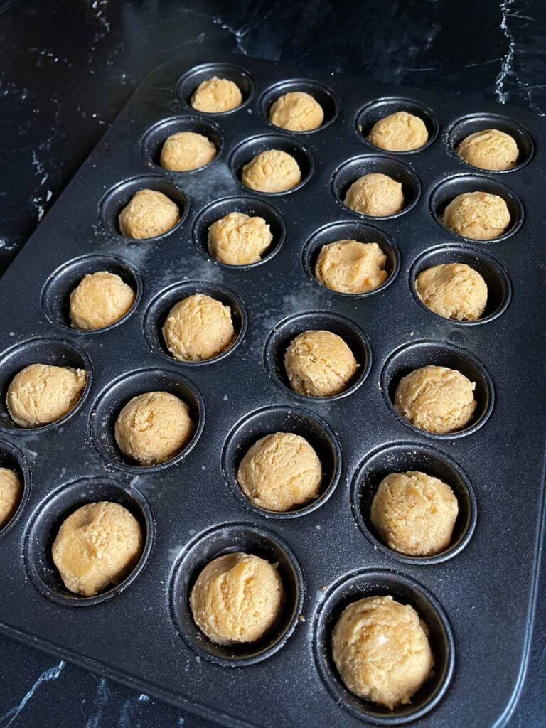 Peanut butter cup cookie dough balls in the mini muffin pan.
