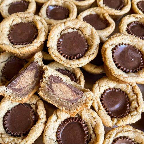 Peanut butter cup cookies placed close to each other with one cut in half showing the inside.