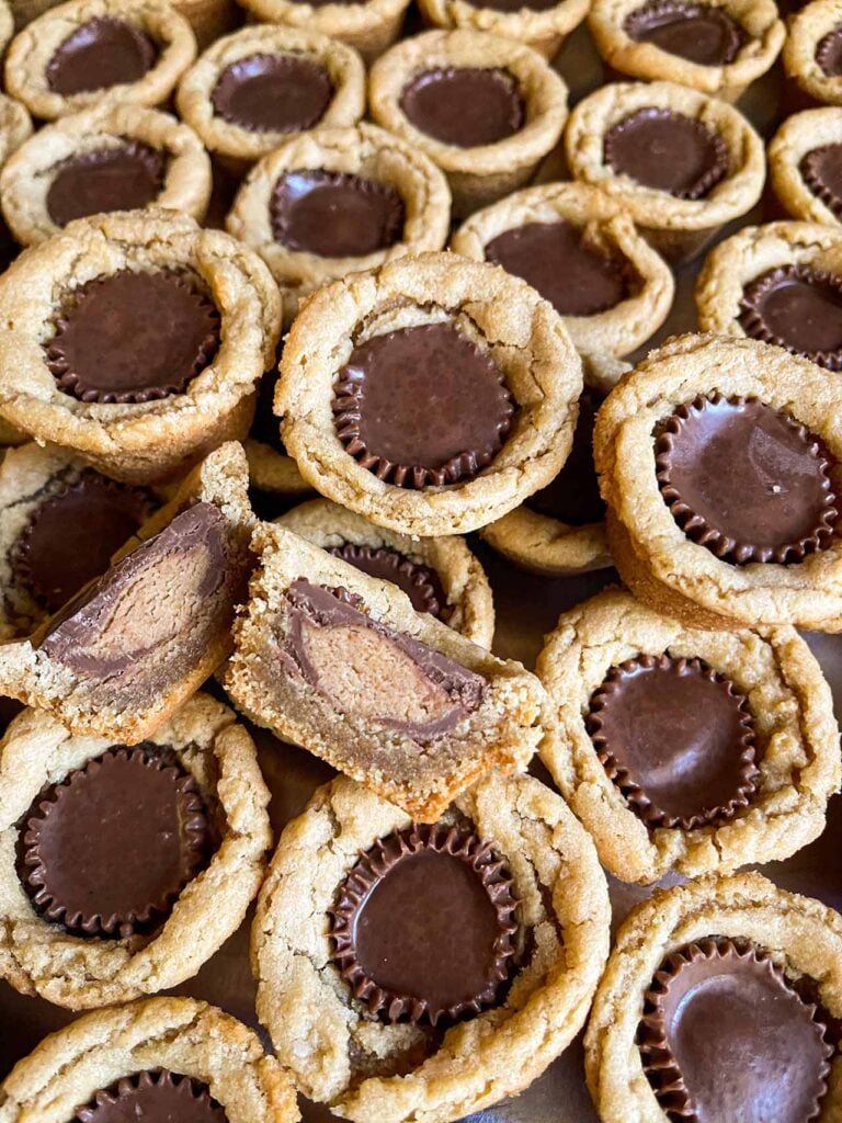 Peanut butter cup cookies placed close to each other with one cut in half showing the inside.