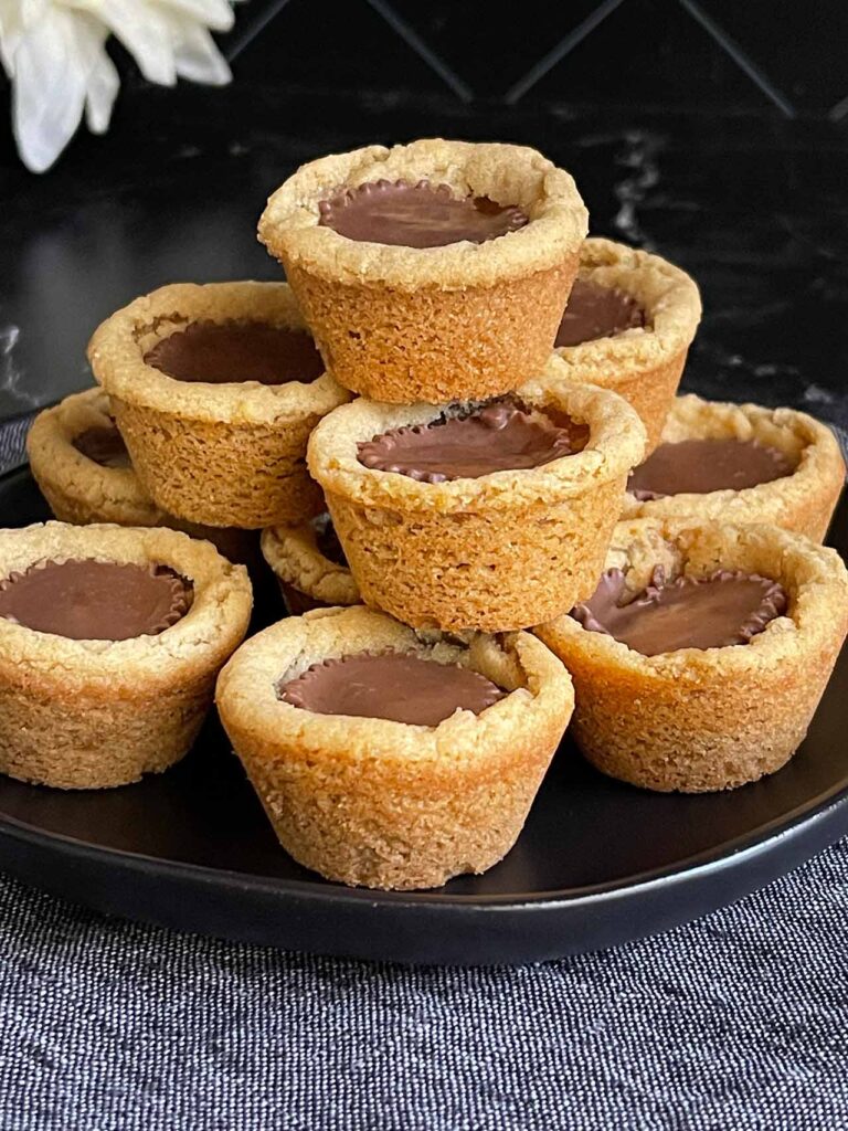 Peanut butter cup cookies stacked on a dark plate.