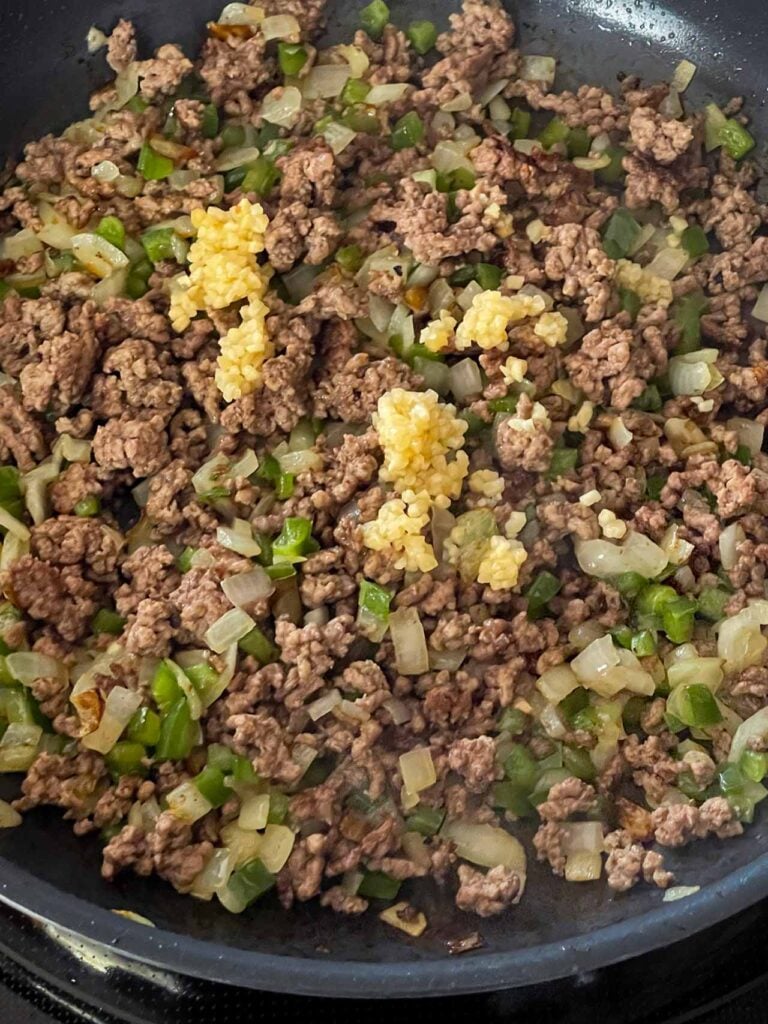 Cooked ground beef with onions, garlic, and jalapenos in a skillet.