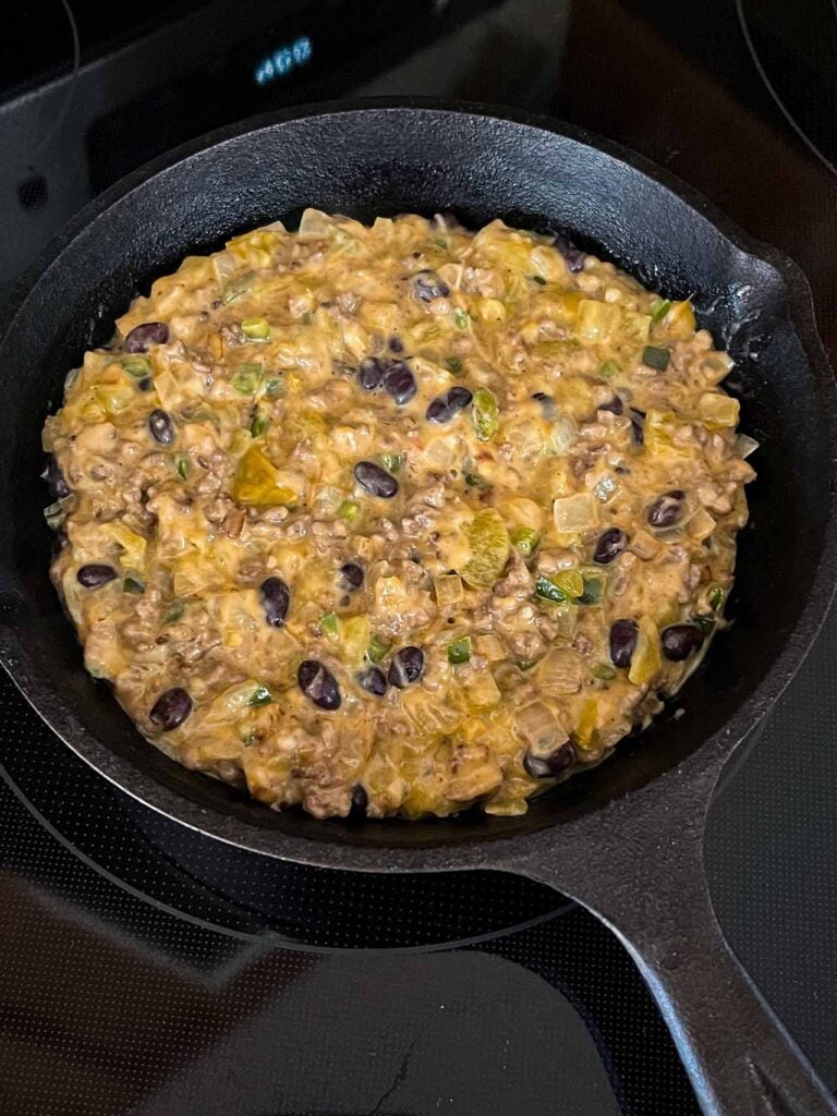 Queso fundido in a cast iron skillet about to go into the oven.