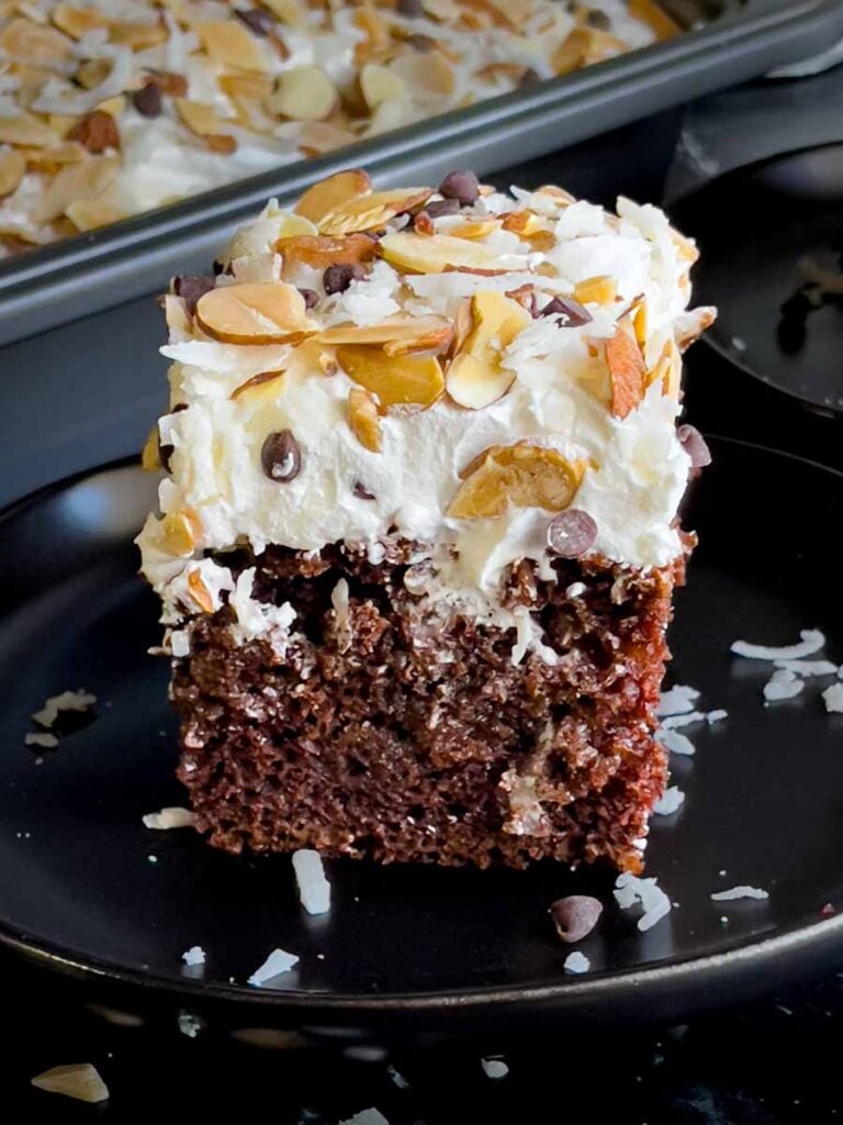 Slice of Almond Joy cake on a dark plate.