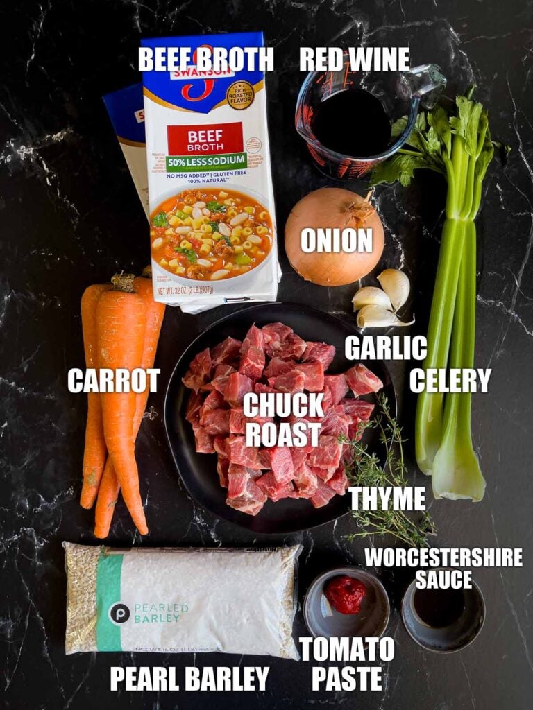 Ingredients for beef barley soup on a dark background.