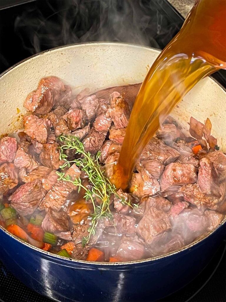 Beef broth being added to the beef barley soup.