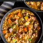 Beef barley soup in a dark bowl.