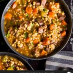 Beef barley soup in a dark bowl.