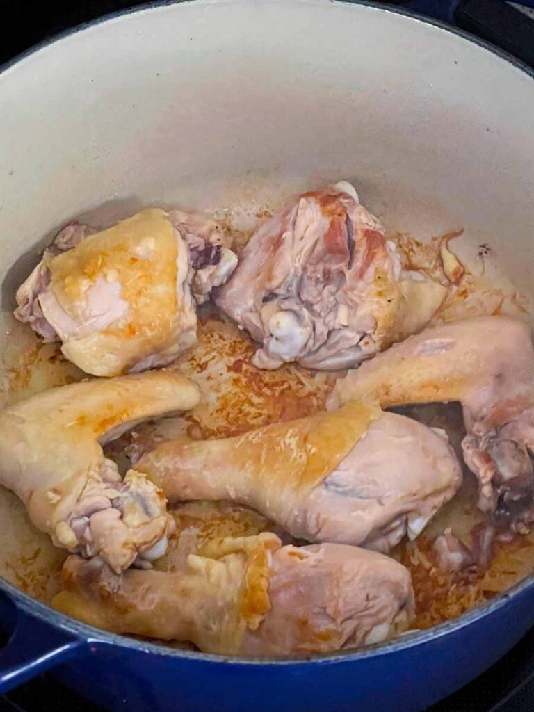 Chicken being browned in a dutch oven.