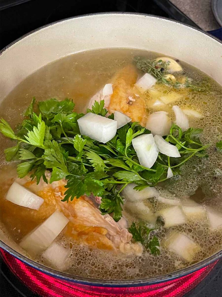 Chicken stock being cooked in a dutch oven.