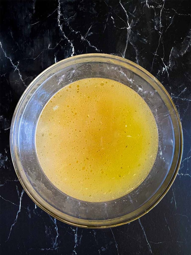 Homemade chicken stock in a glass bowl.