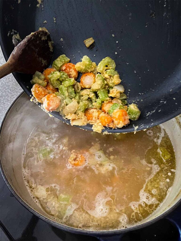 Cooked vegetable roux being added to chicken stock.