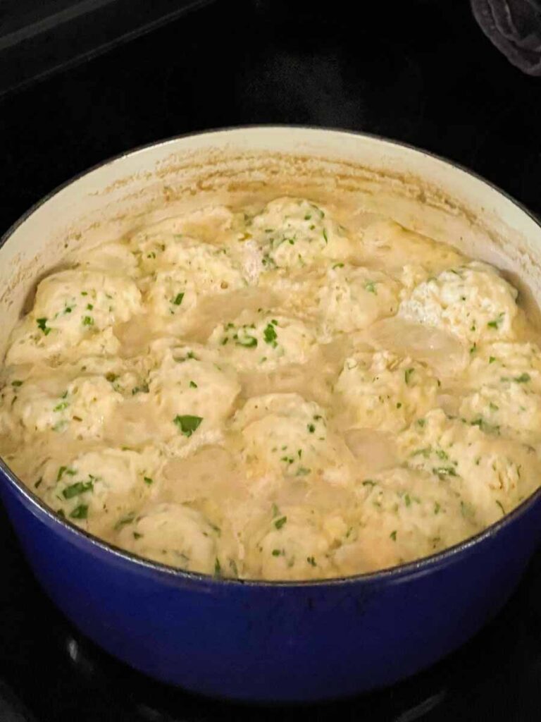 Chicken and dumplings cooking in a dutch oven.