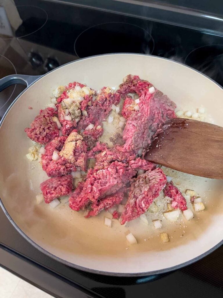 Beef and onions cooking in a cast iron skillet.