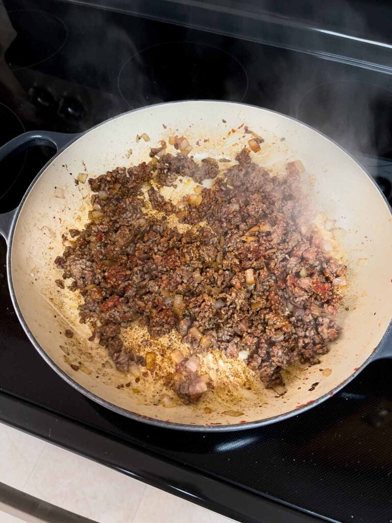Cooked ground beef with spices cooking in a cast iron skillet.