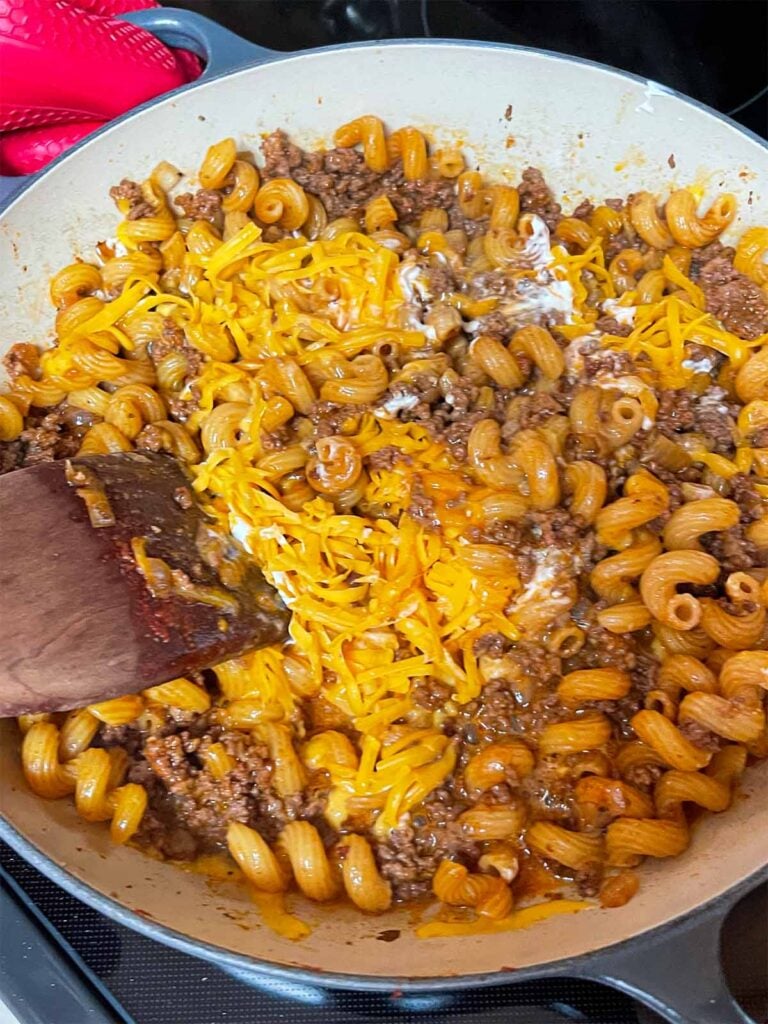 Mixing the ingredients for homemade hamburger helper together in a cast iron skillet.