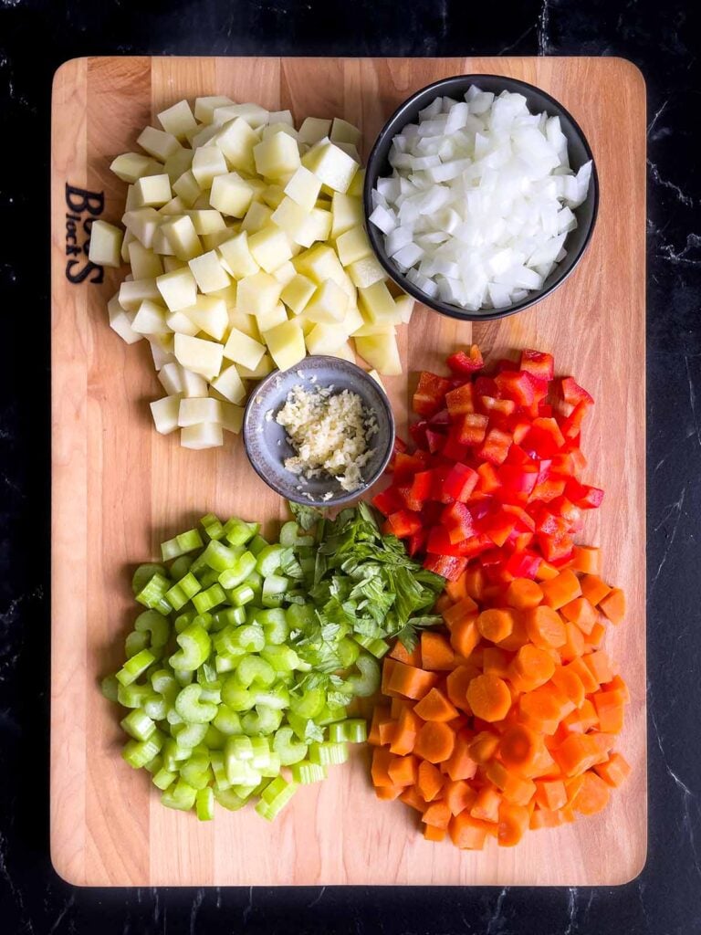 Vegetables for Sicilian chicken noodle soup prepped on a wooden cutting board.