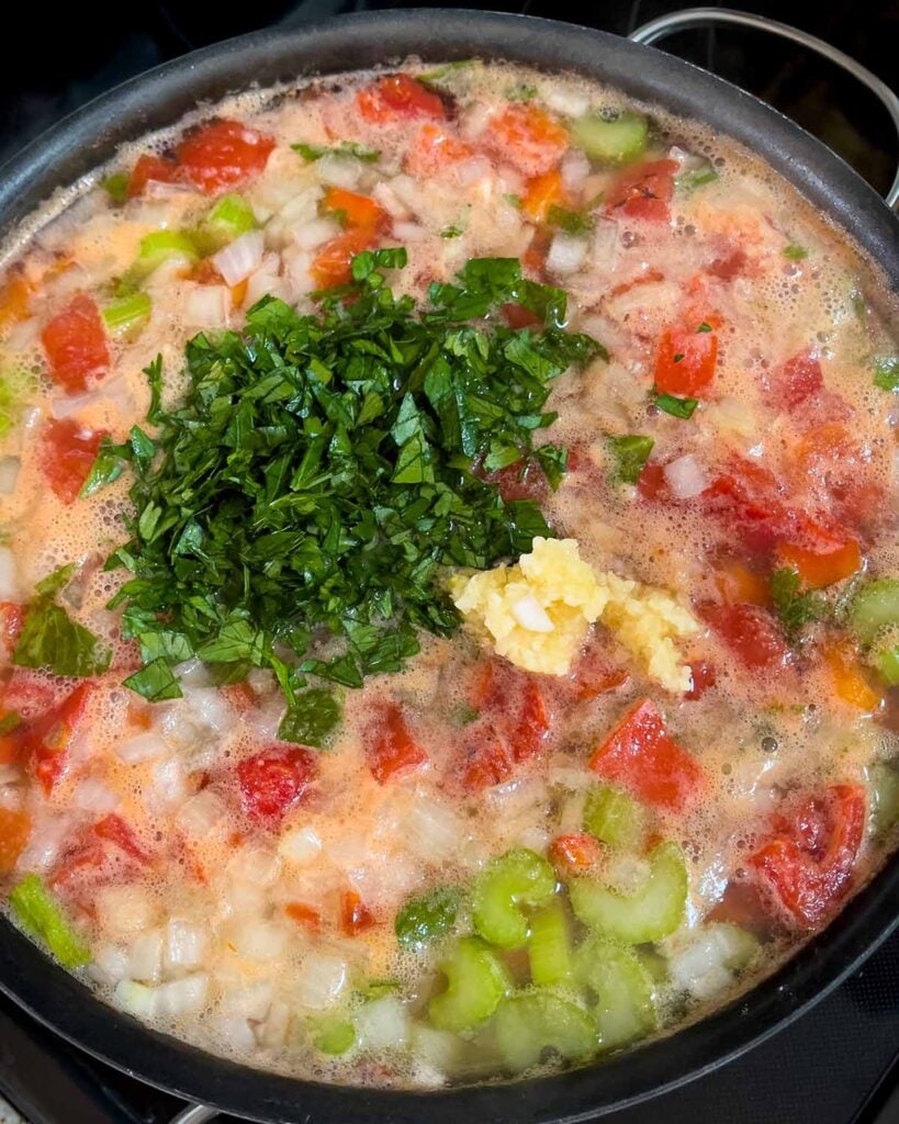 Pot of Sicilian chicken noodle soup simmering with the parsley and garlic added.