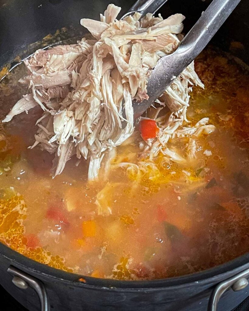 Shredded chicken being added back to the stock pot.