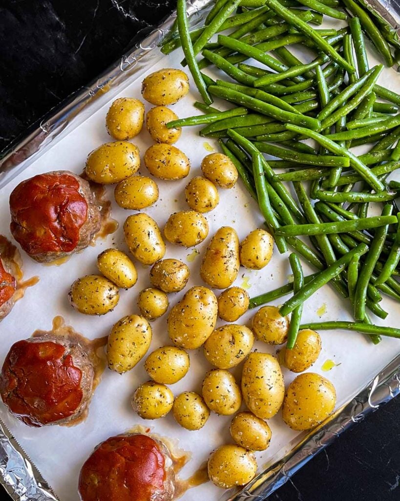 The green beans added to the baking sheet with the mini meatloaves and potatoes.
