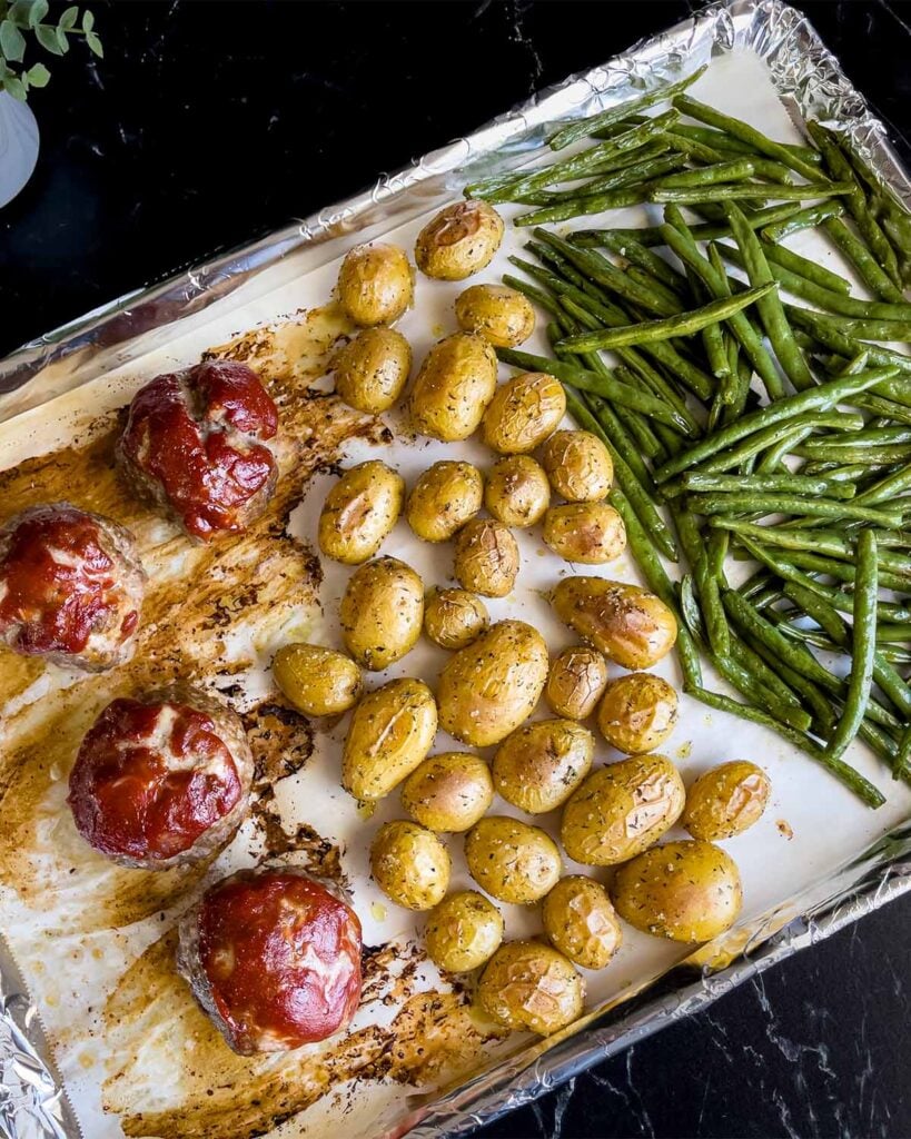 Sheet pan mini meatloaves with green beans and potatoes after cooking.