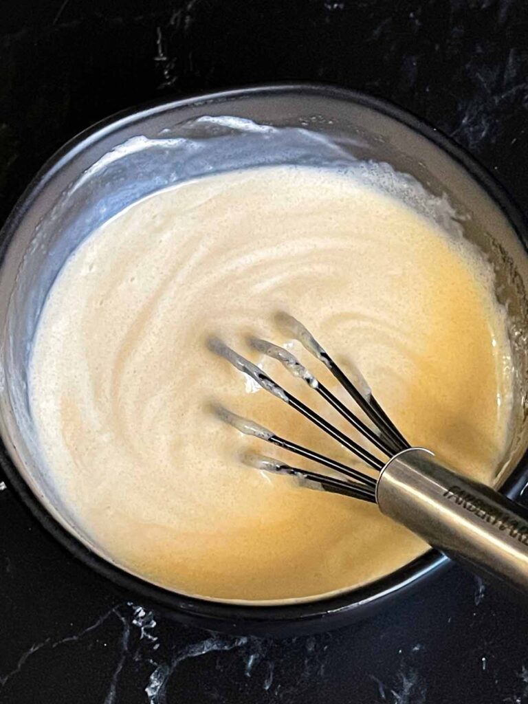 Broccoli salad dressing ingredients combined in a dark bowl.