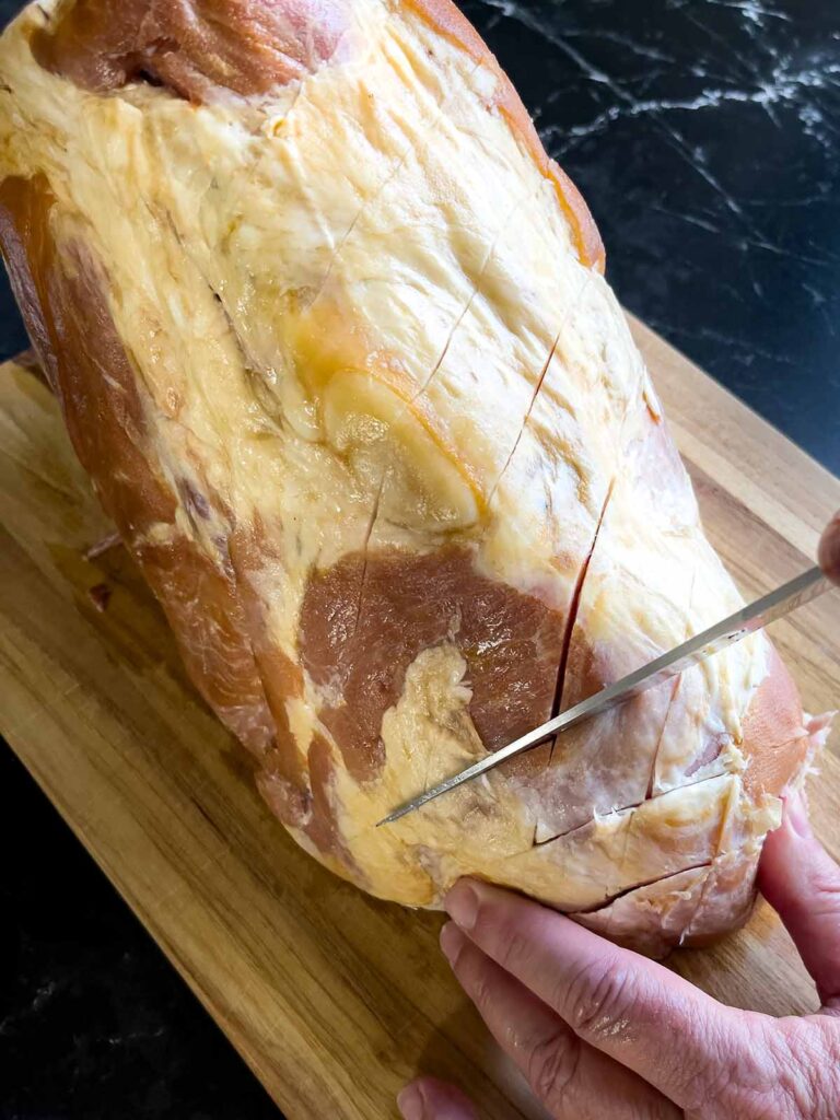 Diagonal slices being cut into the ham to make a diamond pattern.