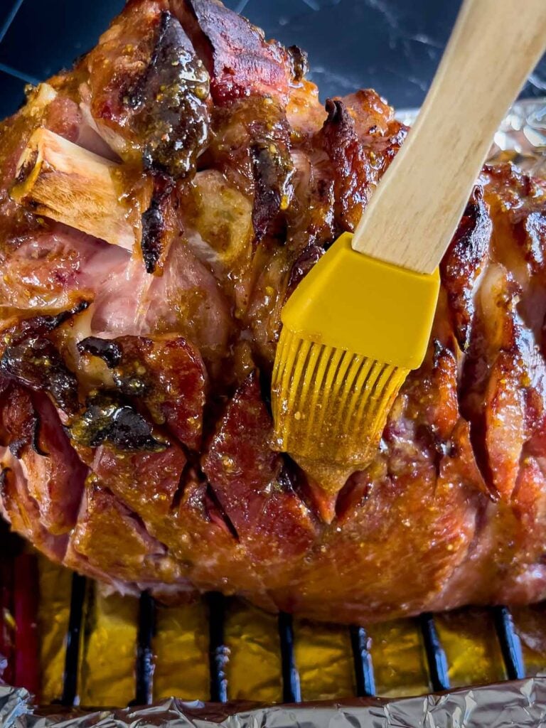 Brown sugar glaze being brushed on the baked ham.